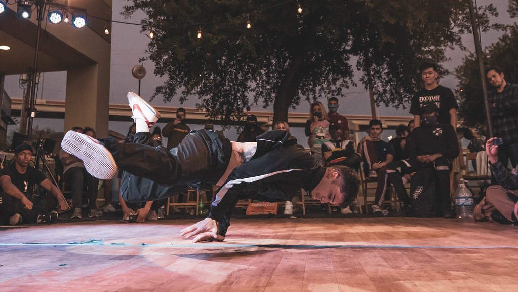 A breakdancer spinning low on the floor at a night-time jam