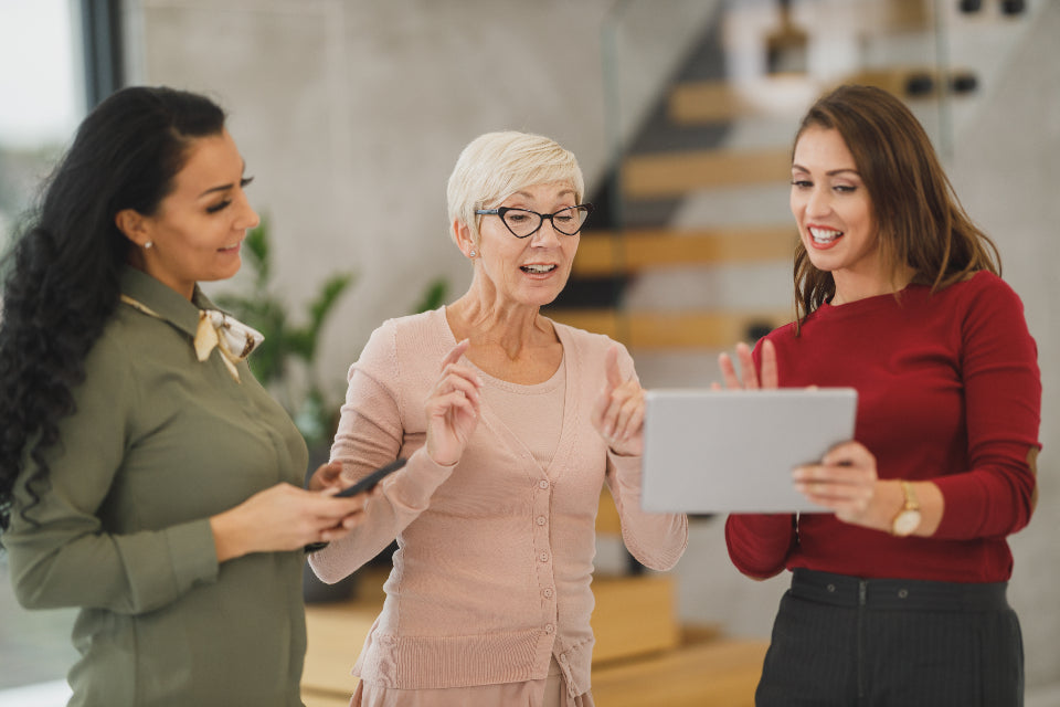 Three women looking at a tablet together in an office
