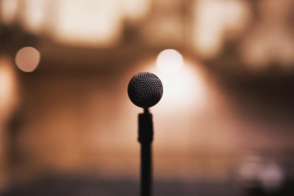 A microphone on a stand against warm stage lights