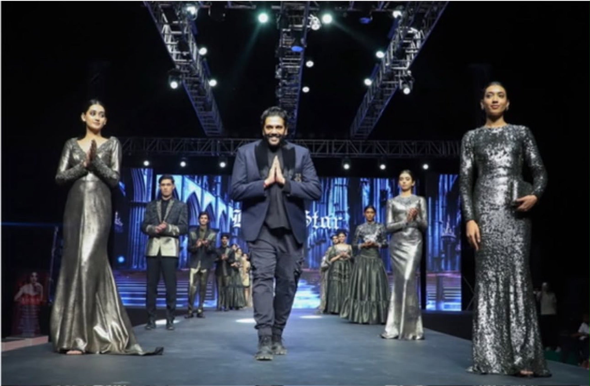 A designer taking the runway at a Youth Fashion show, models either side