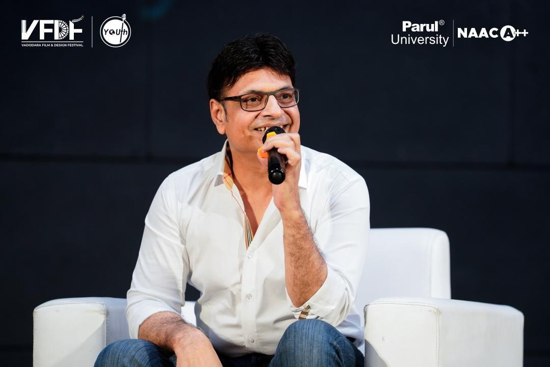 A guest speaker laughing on stage at the Vadodara Film & Design Festival